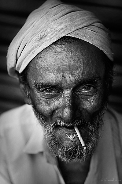 Black and white smiling portrait of an old man with beedi form Kannur