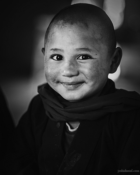 Black and white portrait of a smiling young Buddhist monk in a Monastic school in Hemis, Ladakh