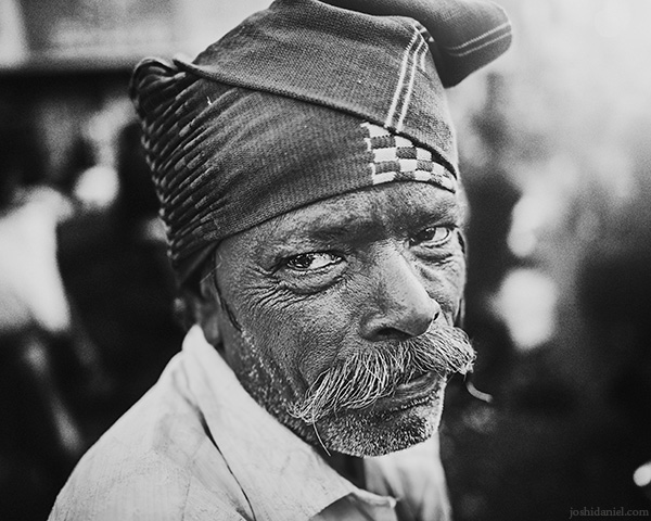 A 28mm wide angle black and white portrait of a street vendor from K. R. Market, Bangalore, Karnataka, India
