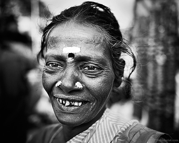 A 28mm wide angle black and white portrait of a smiling flower seller from K. R. Market, Bangalore, Karnataka, India